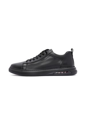 Black low-top leather sneaker with lace-up design, cushioned sole, and visible air cushion in the heel.