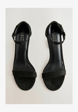 Mustad sametkatted kõrged sandaalid jalasidemega, laia keskosa rihmaga ja sileda nahkpadjaga. Tallad on ümarad ja tasased.