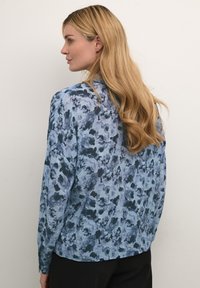 Blusa a maniche lunghe con un motivo floreale blu e blu navy, realizzata in tessuto leggero, con una vestibilità comoda e un semplice design del colletto.