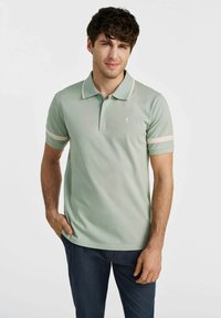 Jasnozielona koszulka polo z kołnierzykiem, krótkimi rękawami z kremowymi paskami oraz małym logo na piersi, wykonana z miękkiego materiału.