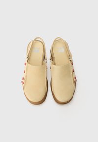 Gele suede slingback schoenen met een ronde teen, platte zool en versierd met rode knopen op een stoffen band. Lichtgewicht en minimalistisch ontwerp.