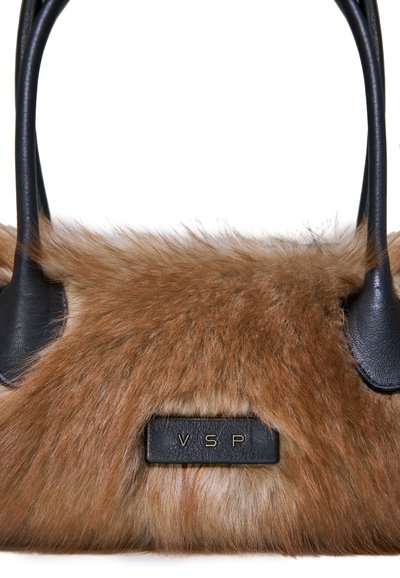 Sac à main en fourrure marron avec des poignées en cuir noir et un patch noir portant l'inscription VSP sur le devant.