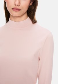 Helles rosa, geripptes Rollkragensweatshirt mit langen Ärmeln, weicher Textur, nahtlosem Design und figurbetonter Silhouette. Schlichter und minimaler Stil.