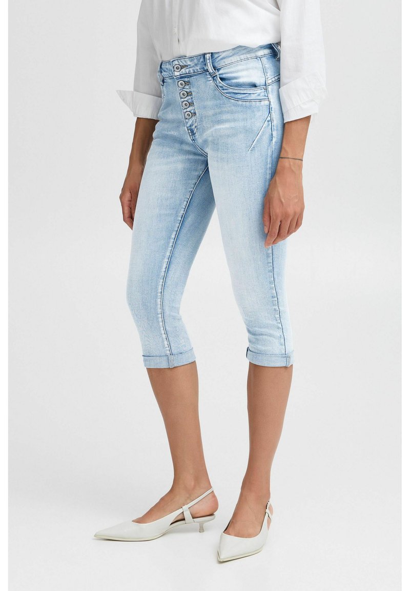 Pantalones capri de mezclilla azul claro con un diseño ajustado, cierre de cinco botones y dobladillos enrollados. Textura suave, detalles de costura clásicos.