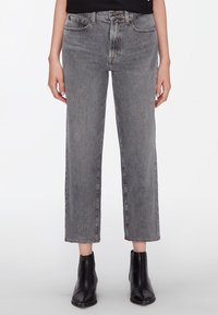 Jeans grises de tiro alto con pierna recta, longitud recortada, cinco bolsillos y detalles de costura sutiles. Llevados con botines negros.