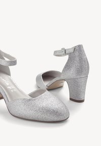Escarpins à talons blocs fermés pour femmes, recouverts de paillettes argentées, avec brides à la cheville, vus de face et de dos sur fond blanc.