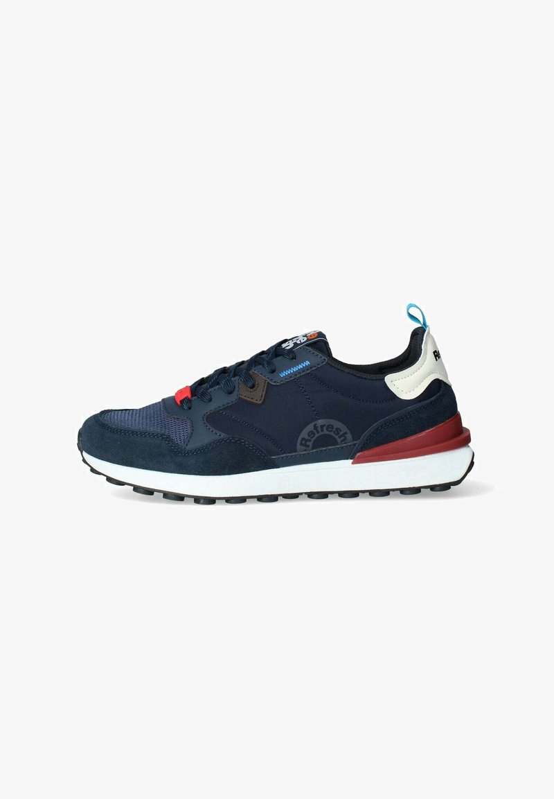 Sneaker blu navy con dettagli in suede e mesh, caratterizzato da dettagli rossi e blu, suola intermedia bianca e suola esterna nera testurizzata con un logo.