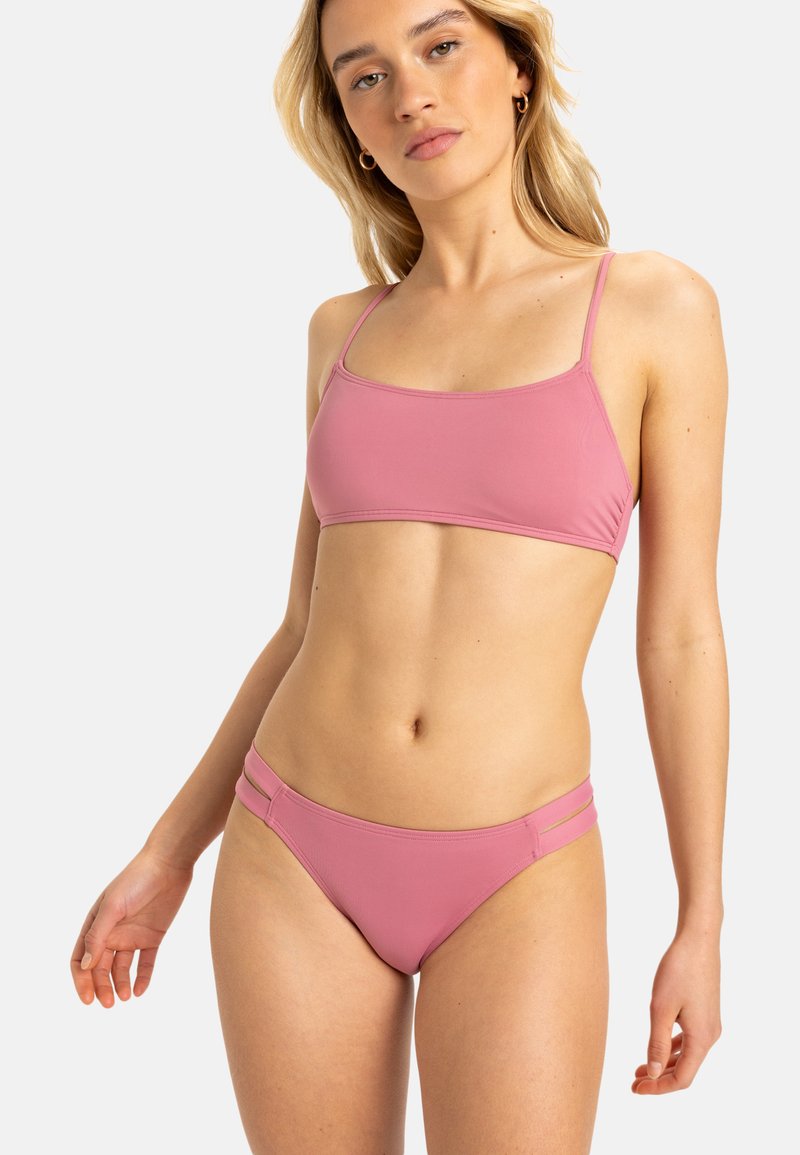 Růžový bikini set s lehce texturovaným braletem na topu a s nastavitelnými ramínky, doplněný o odpovídající nízko pasové kalhotky s dvojitými bočními popruhy.