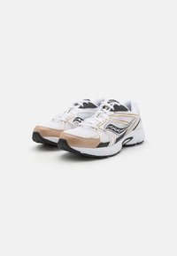 Scarpe da ginnastica bianche con accenti neri e beige, dotate di una parte superiore in rete, suola imbottita e lacci. Dettagli notevoli includono un design curvo.