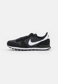Sneaker nero e grigio con tomaia in mesh e suede, logo Nike bianco, suola in gomma nera e design con punta rotonda.