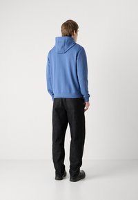 Lyseblå hettegenser og svarte jeans med rett passform, laget av bomullsblanding, med ribbede mansjetter og sidelommer.