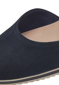 Chaussure sans lacets en daim noir avec bout arrondi, doublure intérieure beige et semelle blanche avec bordure noire.