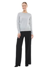 Jasnoszary sweter z okrągłym dekoltem, połączony z czarnymi szerokimi spodniami cargo z bocznymi kieszeniami i gładką fakturą.