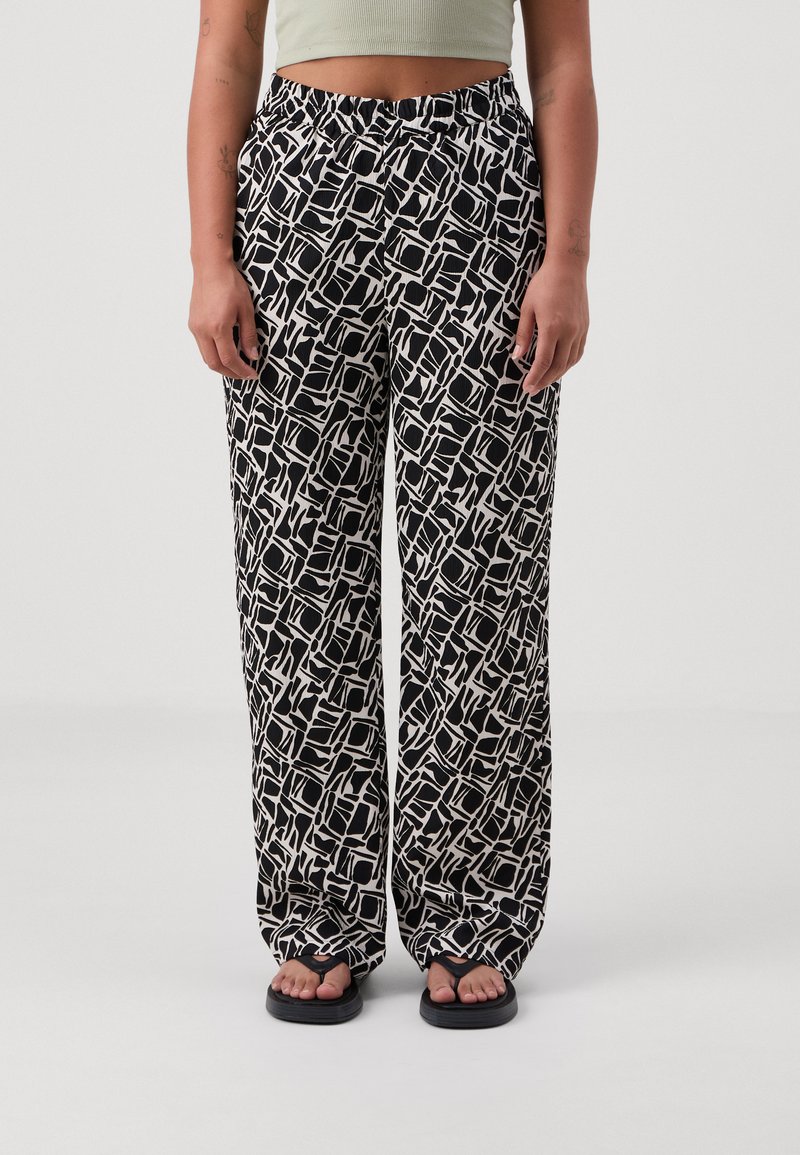 Pantaloni a gamba larga a fantasia bianca e nera con una cintura elastica e un tessuto morbido, caratterizzati da un design geometrico e una vestibilità rilassata.