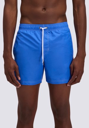 Torace e gambe maschili che indossano pantaloncini da bagno blu brillante con coulisse bianca in vita su sfondo chiaro uniforme.