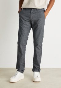 Gray textured trousers with a slim fit, featuring a flat front and side pockets, paired with white sneakers for a casual look.