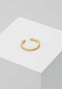 Anillo abierto en tono dorado que presenta una fila de piedras claras y brillantes a lo largo de la mitad de su circunferencia; acabado liso con bordes texturizados.
