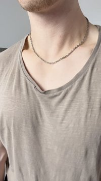 Γκρίζο, ελαφρώς τσαλακωμένο, κοντομάνικο πουκάμισο με βαθύ ντεκολτέ. Ένα ασημένιο κολιέ με ωοειδή links κρέμεται στον λαιμό.