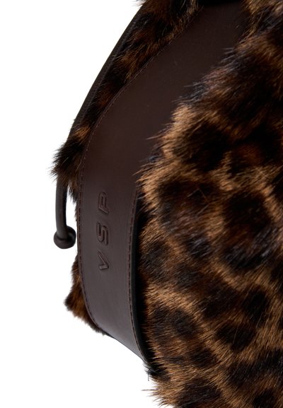 Torba z sztucznego futra w desenie lamparta, akcentowana brązowymi skóropodobnymi paskami i wytłoczonym logo. Charakteryzuje się miękką teksturą i zaokrąglonym kształtem.