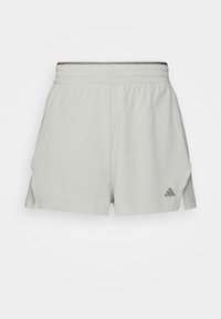 Pantaloni corti sportivi grigio chiaro con un tessuto strutturato, cintura elastica, fessure laterali e un logo Adidas grigio all'orlo.