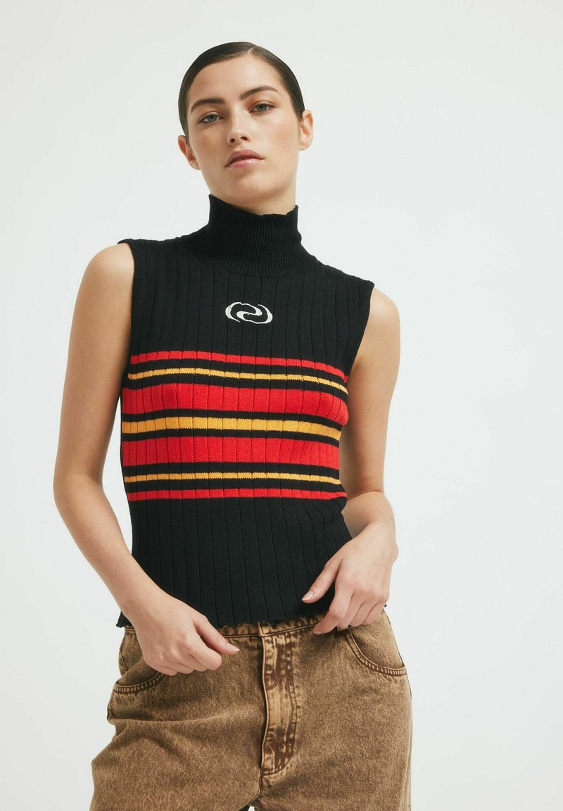 Fekete bordás ujjatlan felső, magas nyakkal, piros, sárga és narancssárga vízszintes csíkokkal, valamint kör alakú logóval a mellkason.