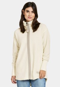 Fleece zip-up jakke i cremé med høj krave, featuring en grå lynlås og ribbede manchetter, løstsiddende pasform og sideskårne i kanten.