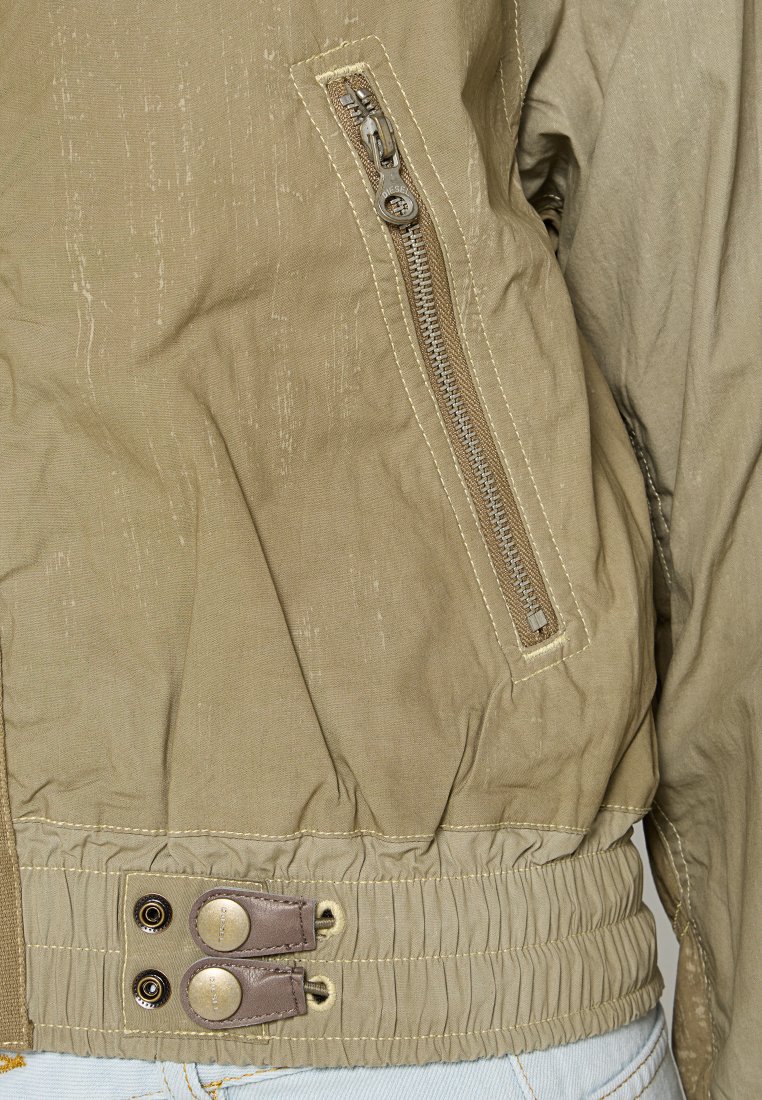 Khaki-Bomberjacke mit strukturierter Oberfläche, seitlicher Reißverschlusstasche, elastischem Saum und zwei Knopfakzenten an der Taille.