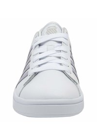 Baskets blanches avec des rayures grises. Elles présentent une tige en cuir lisse, un bout rond, un col rembourré et des lacets plats. Semelle en caoutchouc avec texture.