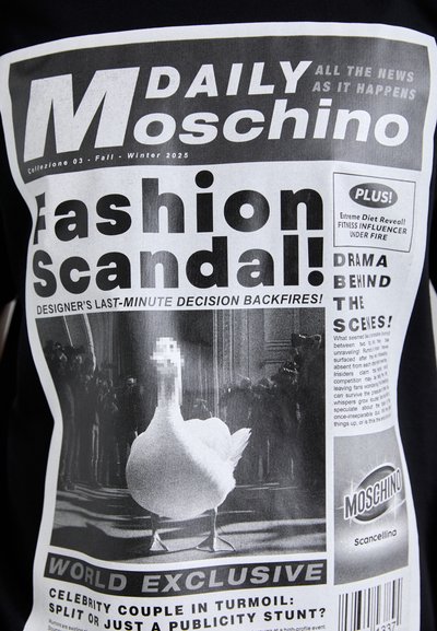 Tricou negru cu un imprimeu grafic în stil ziar. Designul include text alb îndrăzneț și o imagine cu o gâscă, având efecte de pixelizare.