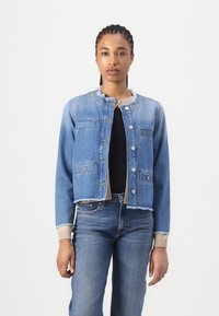Veste en denim bleu clair avec un design cropped, ourlet effiloché et fermetures à boutons argentés ; elle dispose de deux poches poitrine et de poignets côtelés.