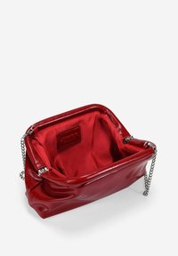 Bolso de mano de piel sintética roja con un diseño estructurado, cadena plateada y forro suave. Presenta una etiqueta interior de la marca.