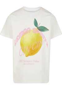 Balta kokvilnas T-krekls ar lielu dzeltena citrona grafiku, rozā tekstu "LEMON SPRITZ CIN CIN" un informāciju par "1100 Belmonte Palace".