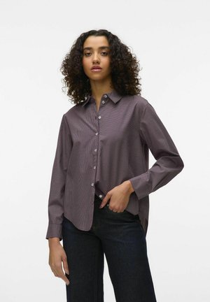 Knapplistad skjorta i ett murrigt rutförmönster, med spetsig krage, långa ärmar och rak passform, kombinerad med mörka denimbyxor.