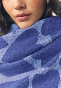 Sciarpa blu con motivo a cuori in diverse tonalità, realizzata in un tessuto morbido e strutturato, drappeggiata intorno al collo.