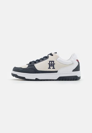 Sneakers con suola in gomma bianca, accenti in pelle blu navy e parte superiore in suede beige. Presentano una chiusura con lacci e un logo sul lato.