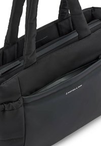 Musta pehmustettu läppärilaukku, jossa on kaksoiskahvat, ulkopuolinen vetoketjupussi ja sileä pinta; sisältää Kapten & Son -logon ja minimalistisen muotoilun.