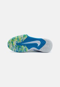 Semelle de chaussure avec un mélange de couleurs bleu, vert, jaune et blanc et des motifs texturés pour une meilleure adhérence, conçue pour un usage sportif.