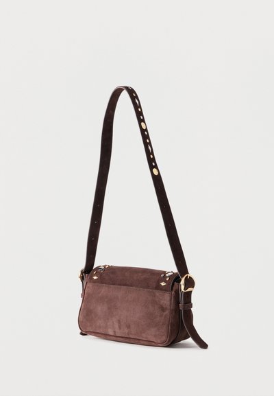 Καφέ σουέντ τσάντα ώμου με χρυσούς τόνους τρουκς στο καπάκι και ρυθμιζόμενο λουράκι με χρυσή πόρπη, εμφανιζόμενη σε ανοιχτό φόντο.