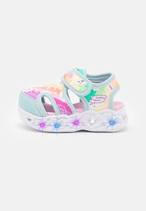 Sandalias infantiles coloridas con un diseño abierto, que presentan tonos pastel, patrones de nubes, una correa de Velcro y una suela blanca y ondulada.