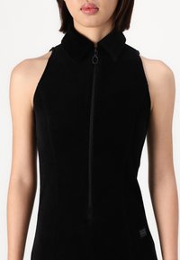 Black sleeveless dress with a collared neck, featuring a front zipper and a tailored fit. Soft texture, no visible patterns or accents.