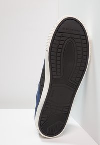 Baskets en toile navy avec une semelle en caoutchouc blanche. Présente une semelle extérieure texturée noire et un design minimaliste. Taille indiquée comme 41.