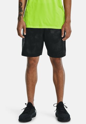 Zwarte sportieve shorts van een gladde stof met een relaxte pasvorm, gecombineerd met een felgroen shirt en zwarte schoenen.