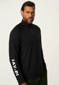 Schwarzes Langarm-Ziptop mit Stehkragen, ausgestattet mit weißem Text "JAY-PI" auf dem linken Ärmel und strukturiertem Stoff.