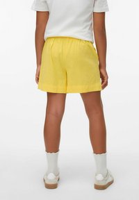 Gula shorts med elastisk midja och rak skärning. Matchade med vita skor och strumpor med vågkant. Enfärgad, lätt tyg.