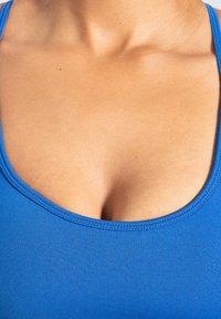 Top azul sin mangas con escote redondeado, confeccionado en una tela suave y elástica. La textura visible y el diseño ajustado resaltan la forma.