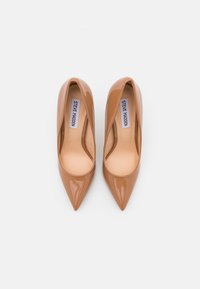 Décolleté a punta in pelle verniciata color nocciola, caratterizzate da una superficie liscia e una silhouette affusolata, con un interno beige e brandizzazione.