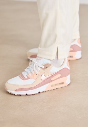 Baskets Nike Air Max blanches, roses et beiges avec un dessus en mesh et cuir, bout rond et une unité de coussin d'air visible dans la semelle.