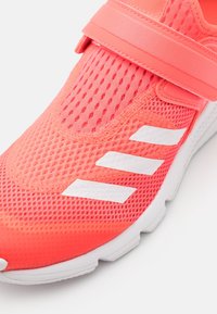 Rosa nätträningsskor med en texturerad ovandel, som har ett brett rem och tre vita ränder på sidan. Vit gummisula.