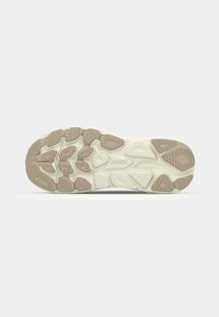 Shoe sole featuring a textured design with a mix of light beige and dark tan rubber, highlighting patterned grip elements and branding.