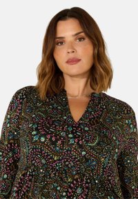 Schwarze Bluse mit einem bunten Paisley-Muster in Blau, Pink und Grün. V-Ausschnitt-Design mit gerafftem Detail am Ausschnitt.